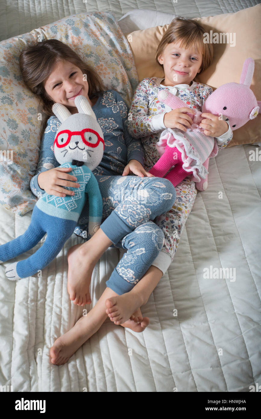 Sisters hugging soft toys on bed Stock Photo Alamy