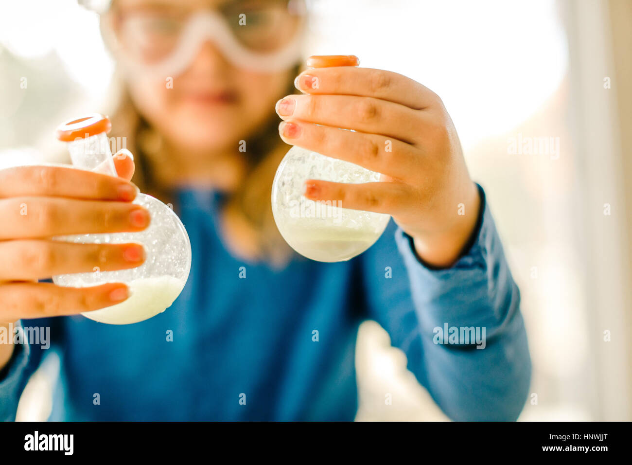 Girl doing science experiment, holding flasks of liquid Stock Photo