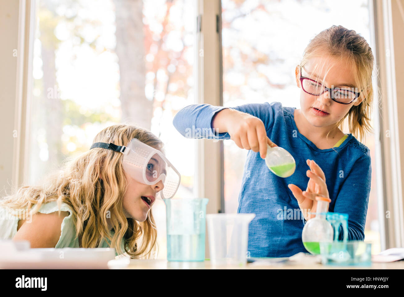 Two girls doing science experiment, shaking liquid in flask Stock Photo