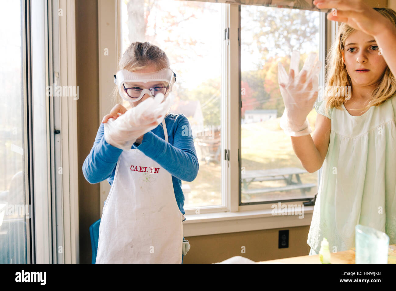 Two girls doing science experiment, putting on large latex gloves Stock Photo