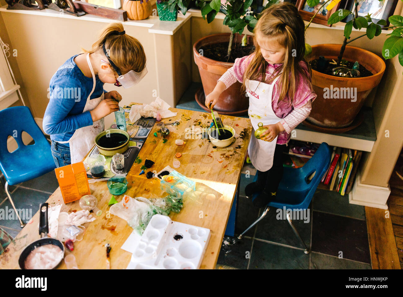 Two girls doing science experiments at messy table Stock Photo