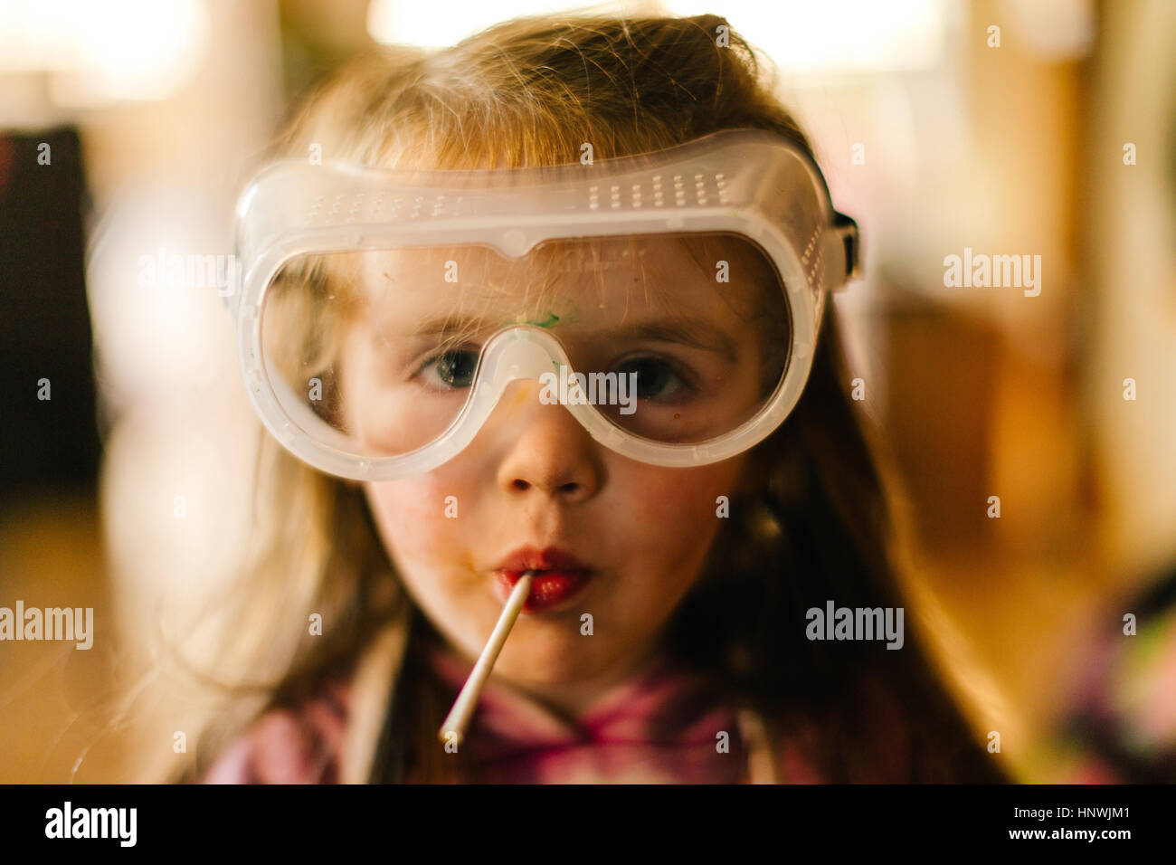 Portrait of girl in safety goggles sucking lollipop Stock Photo