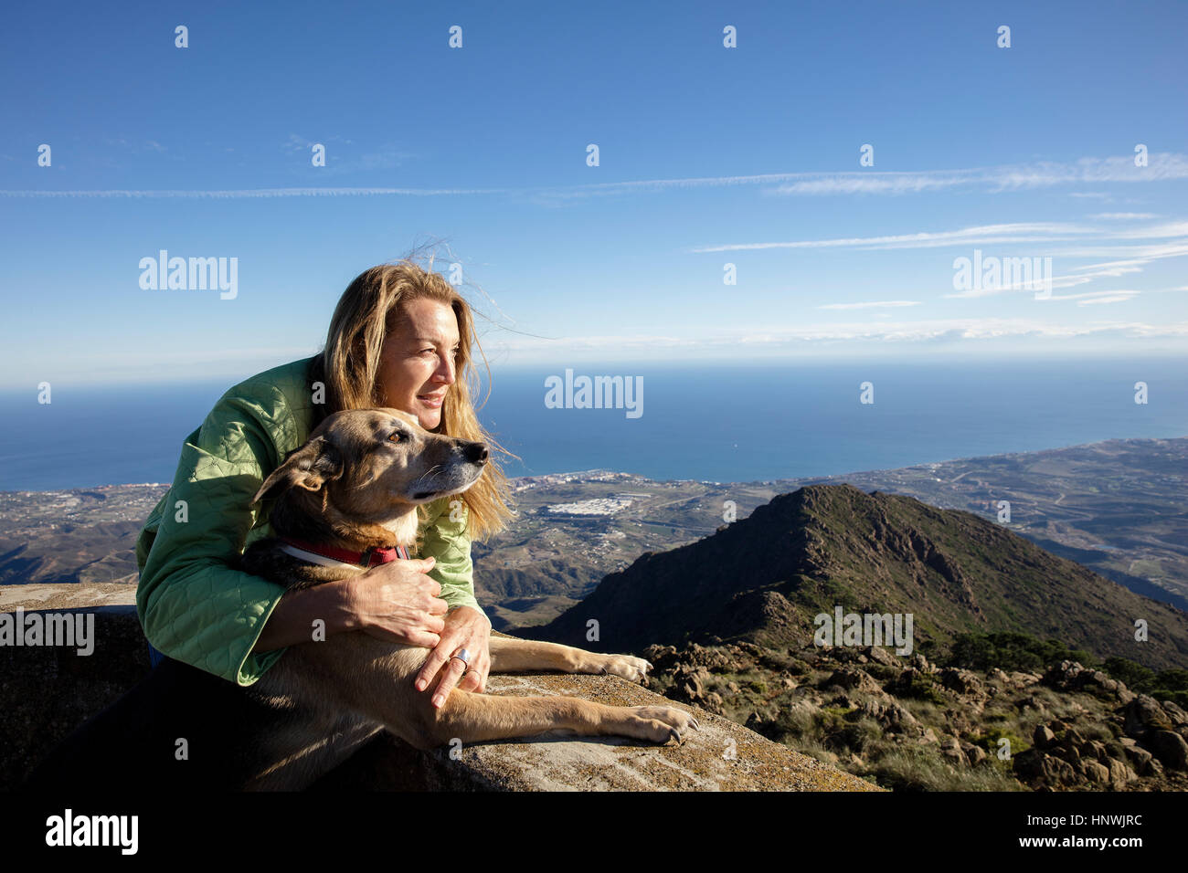 Mature woman and dog looking out from elevated view near coast, Estepona, Spain Stock Photo