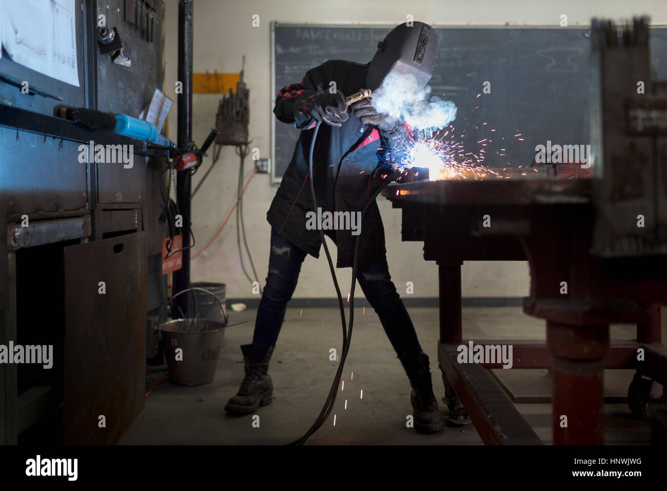 Female metal worker welding at classroom workbench Stock Photo
