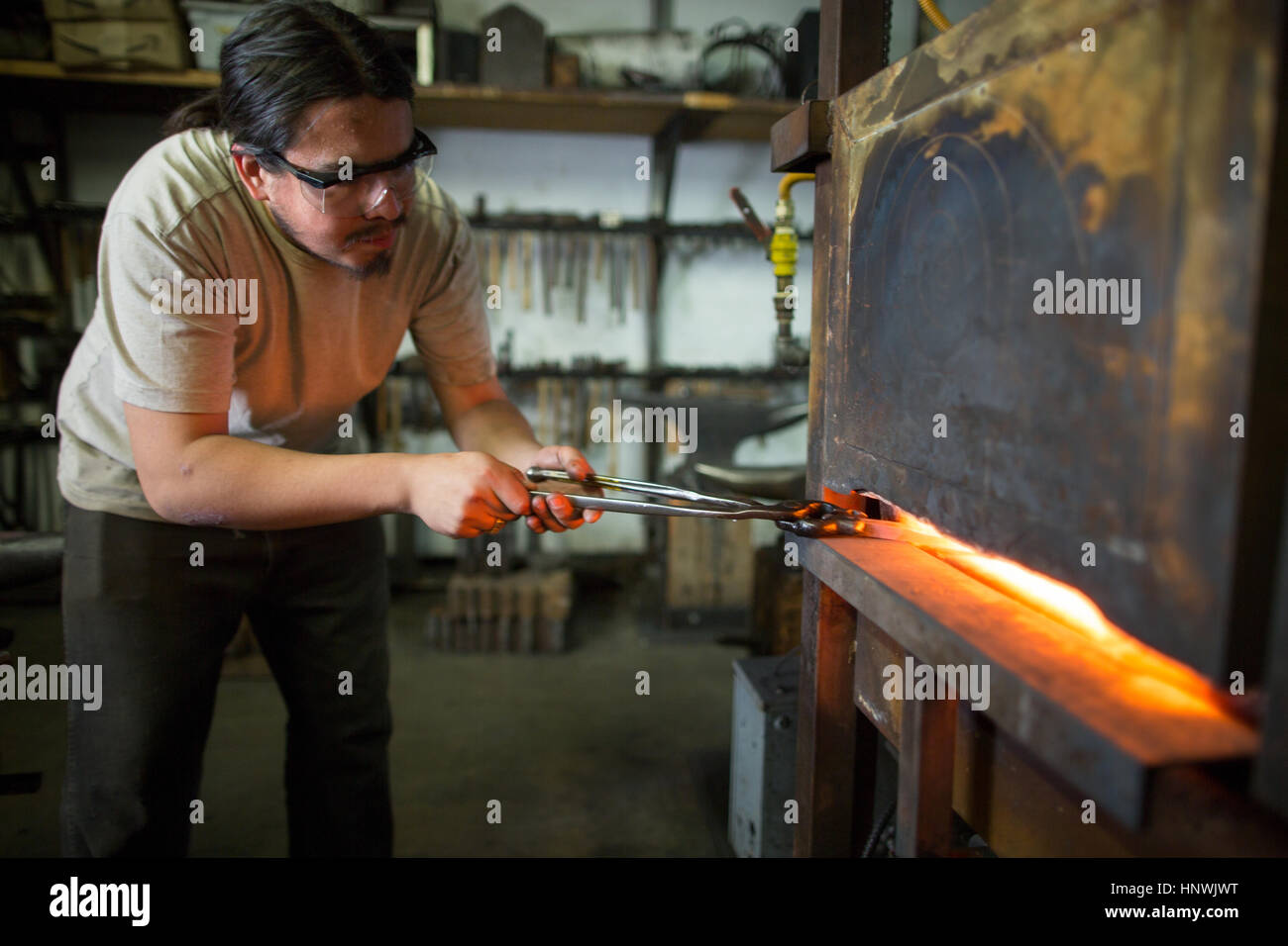 Male metalsmith removing metal workshop furnace Stock Photo