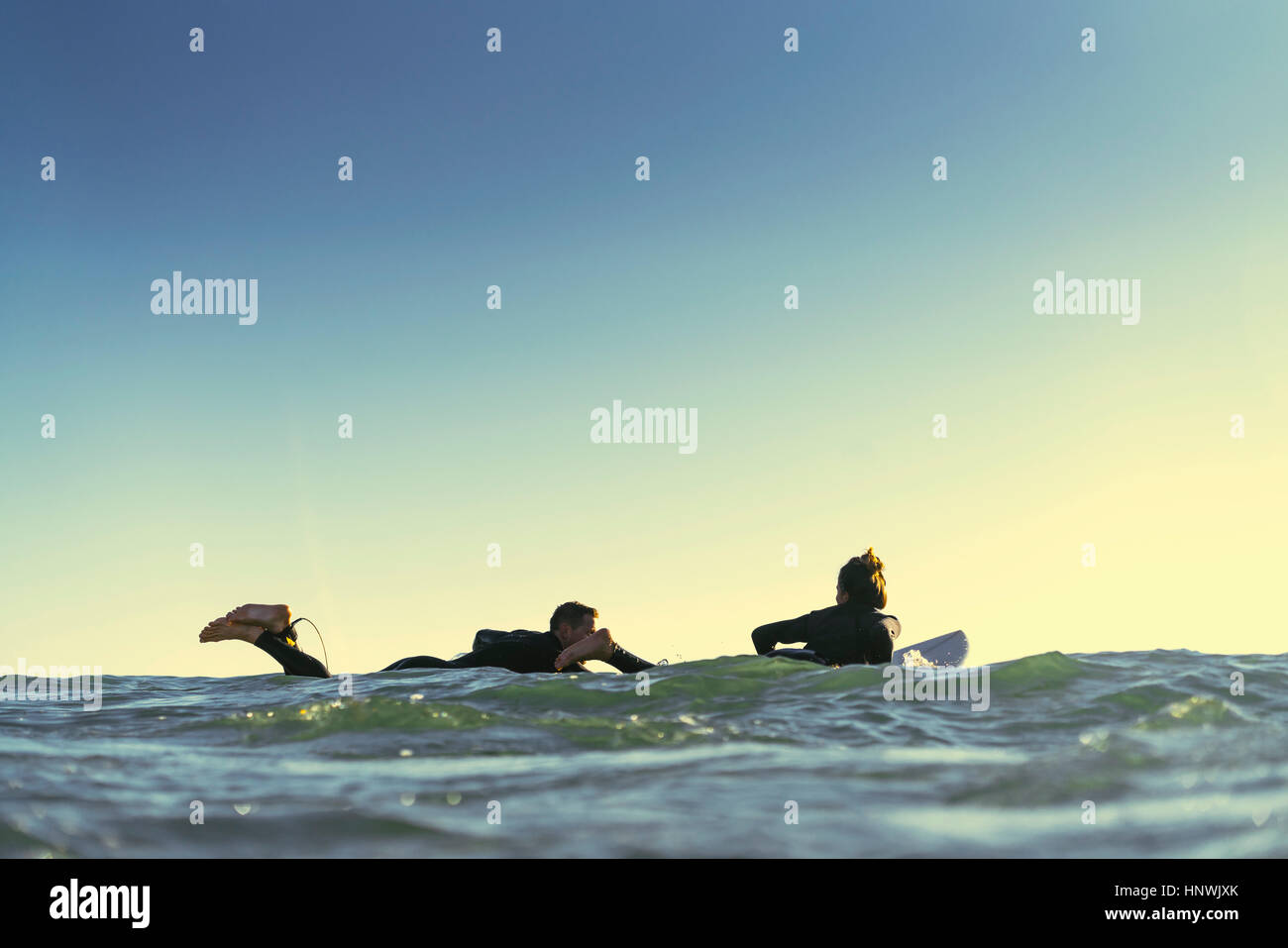 Surfing couple paddling surfboards at sea, Newport Beach, California, USA Stock Photo