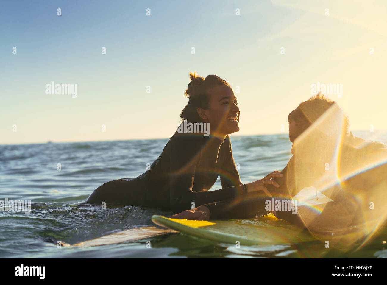 Surfing couple leaning on surfboards in sea, Newport Beach, California, USA Stock Photo