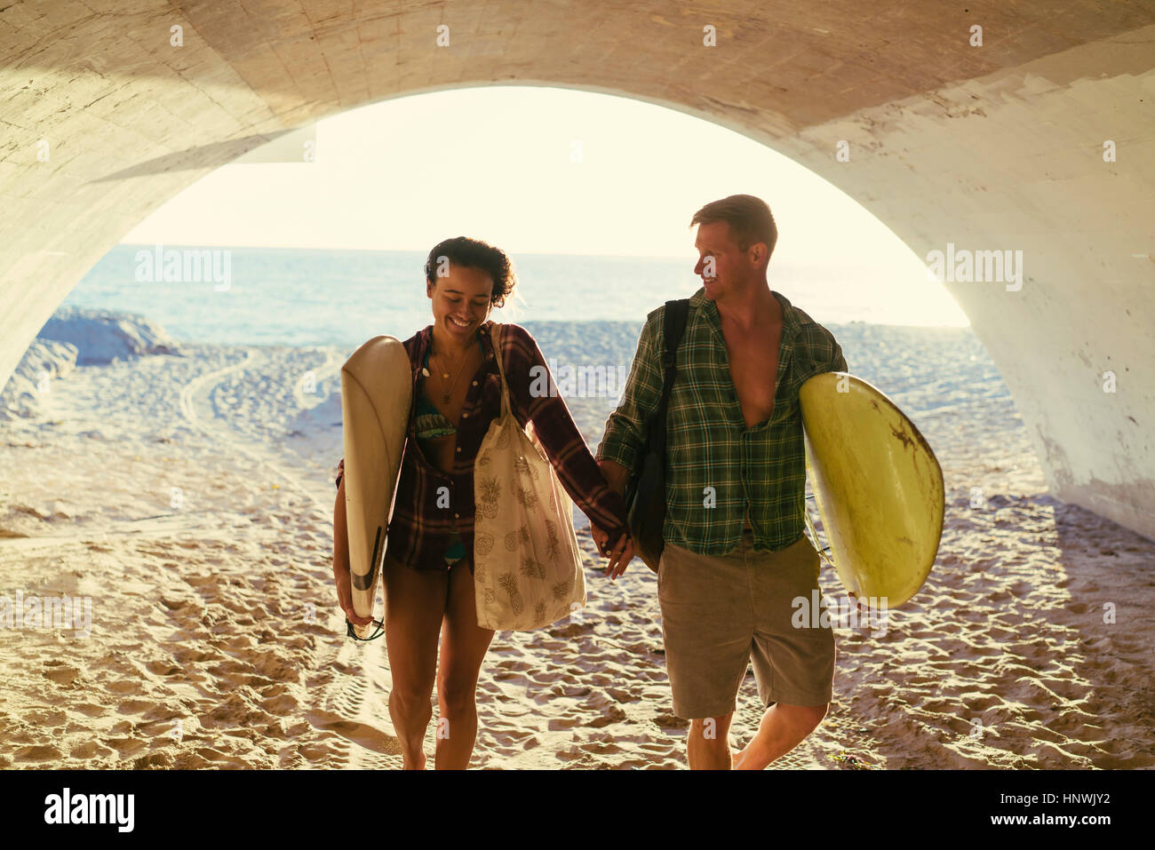 Surfing couple walking in underpass at Newport Beach, California, USA Stock Photo