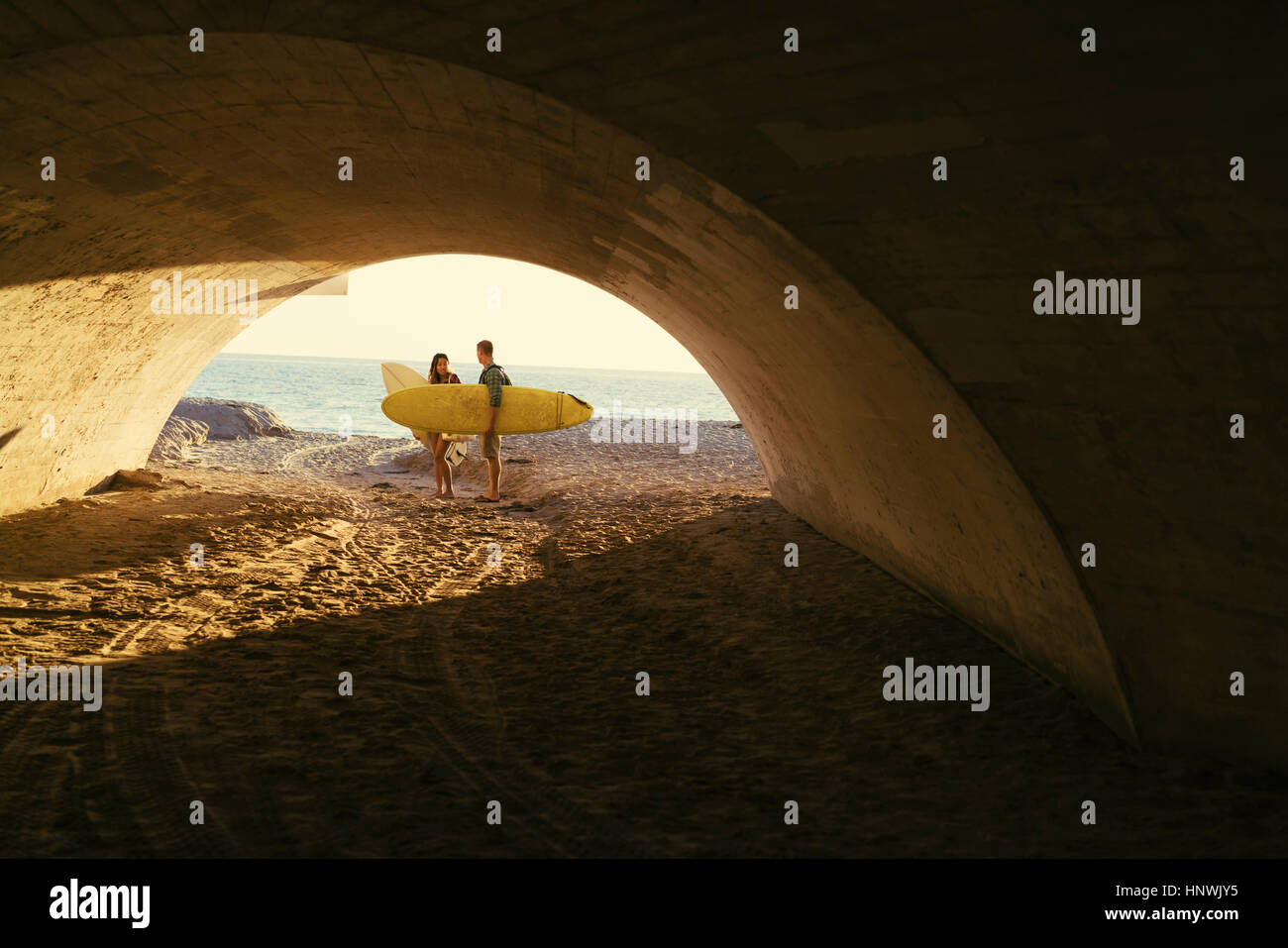 Surfing couple in underpass at Newport Beach, California, USA Stock Photo