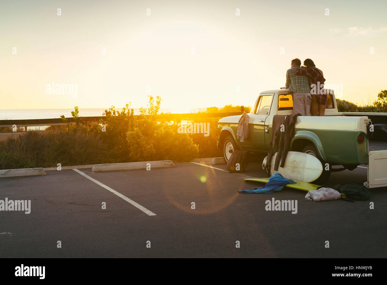 Rear view of couple in back of pickup truck watching sunset at Newport Beach, California, USA Stock Photo