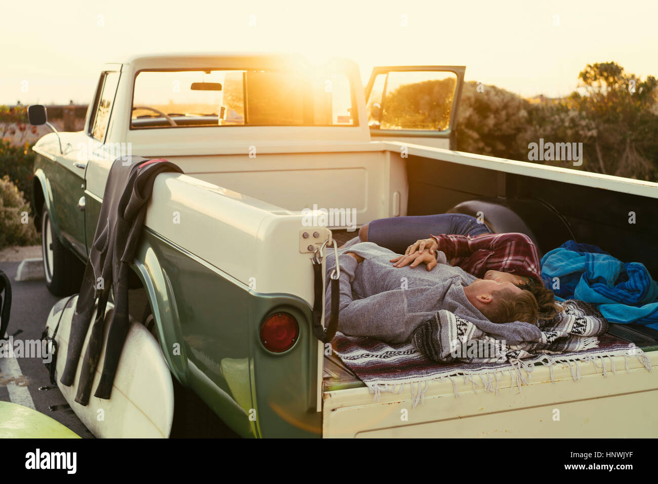 Surfing couple lying in back of pickup truck at Newport Beach, California, USA Stock Photo