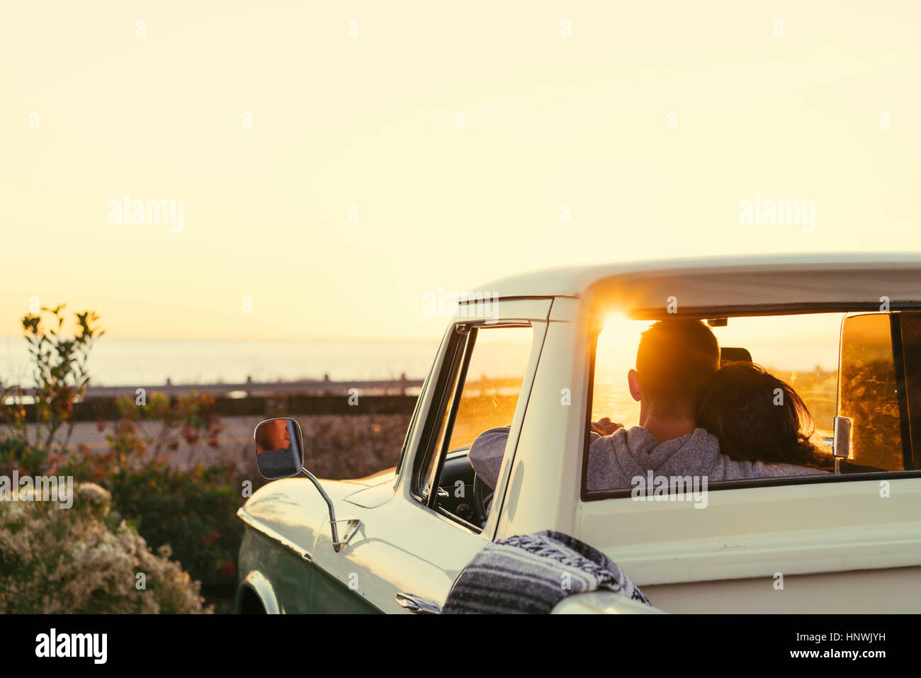 Rear view of couple in pickup truck watching sunset at Newport Beach, California, USA Stock Photo