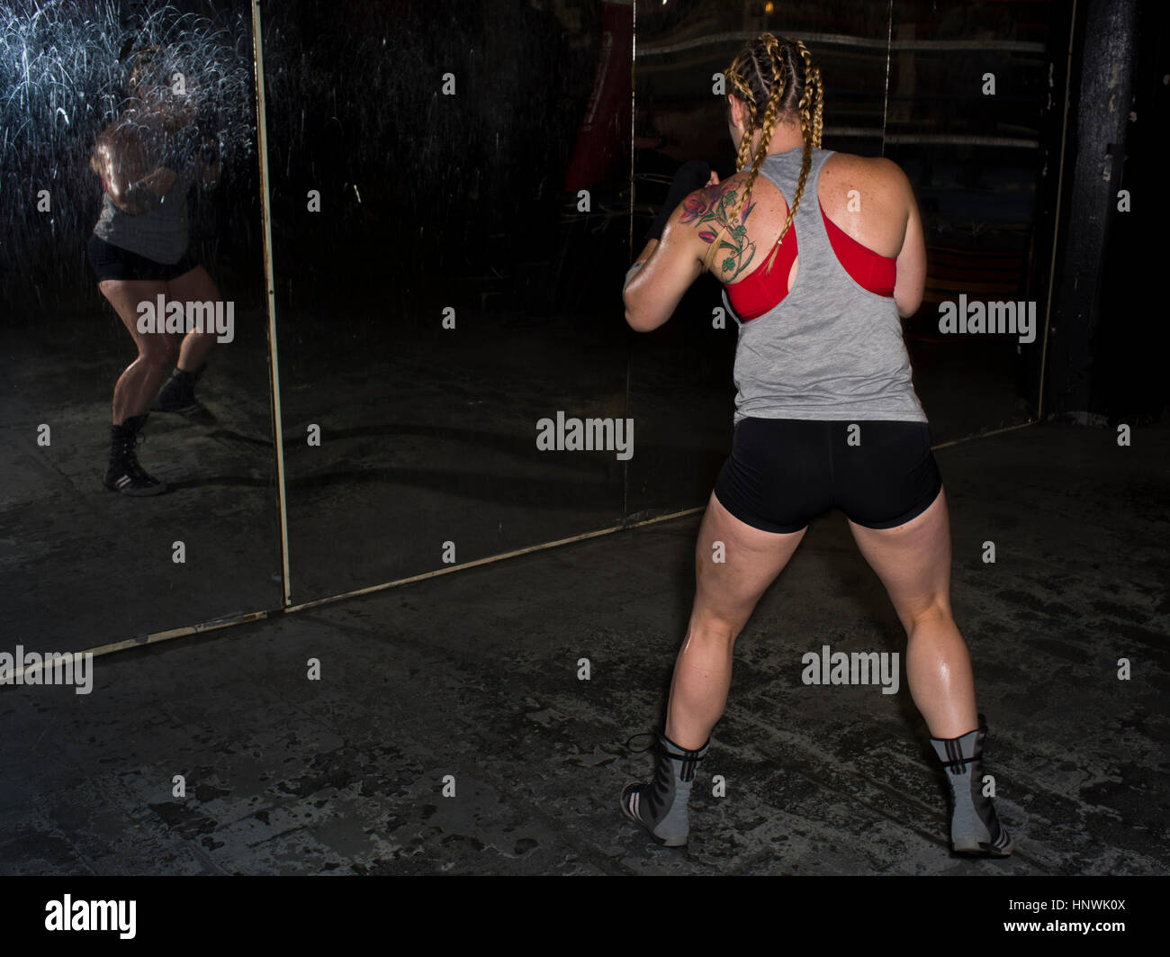 Rear view of female boxer sparring looking in gym wall mirror Stock Photo
