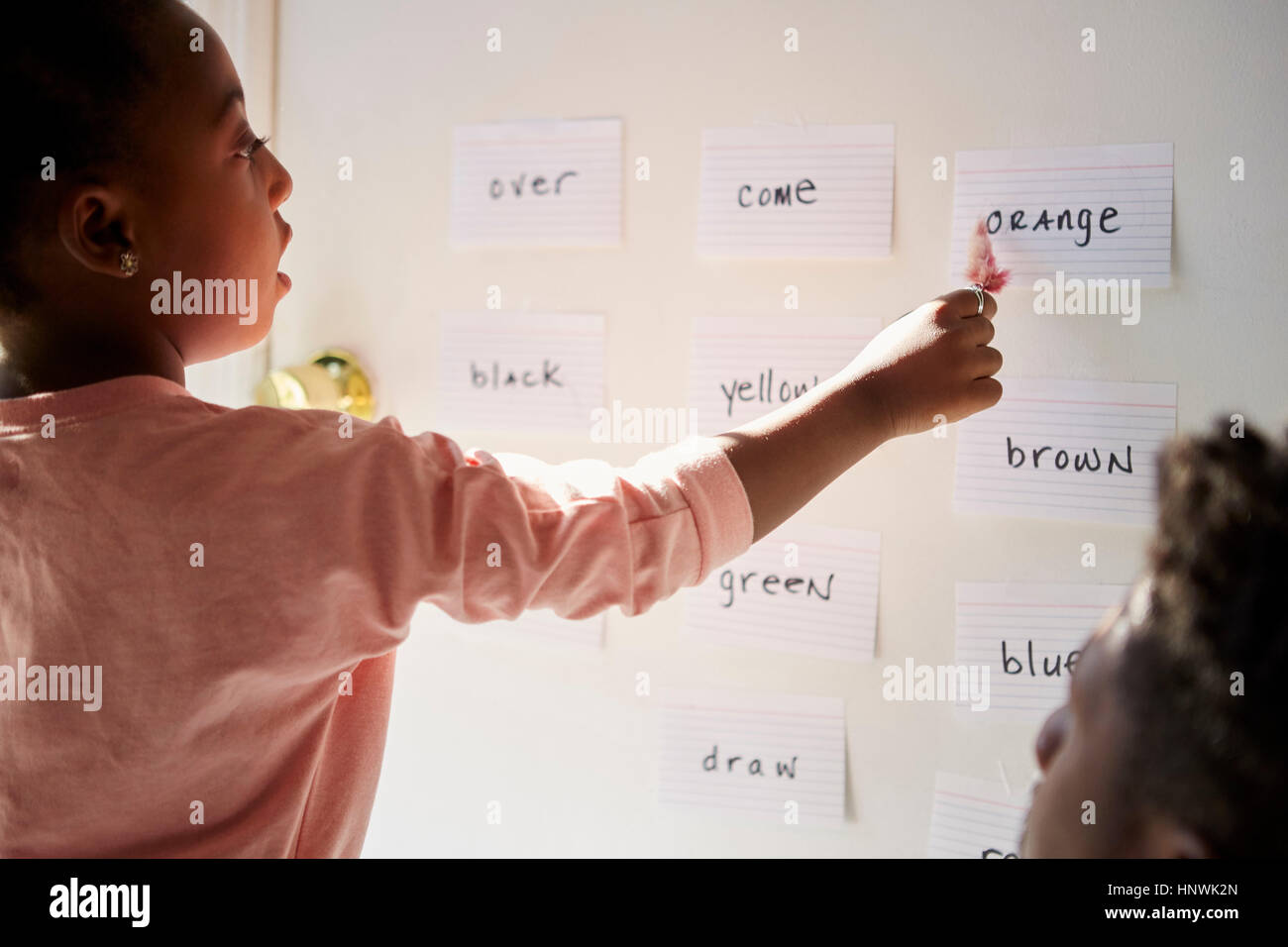 Girl with father pointing at words on wall Stock Photo
