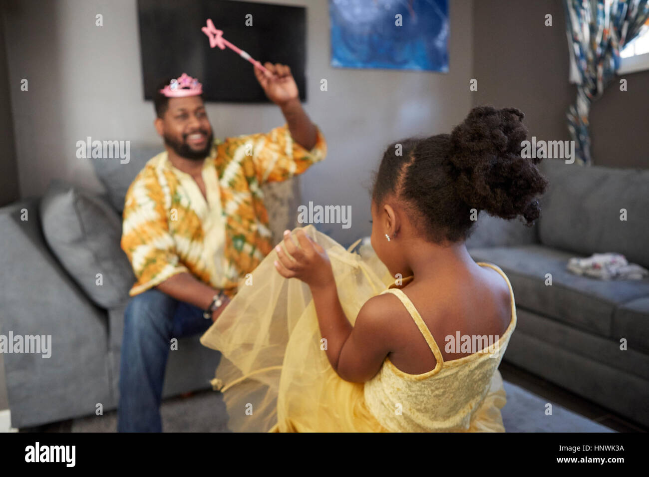 Man casting spell on daughter in fairy costume in living room Stock Photo
