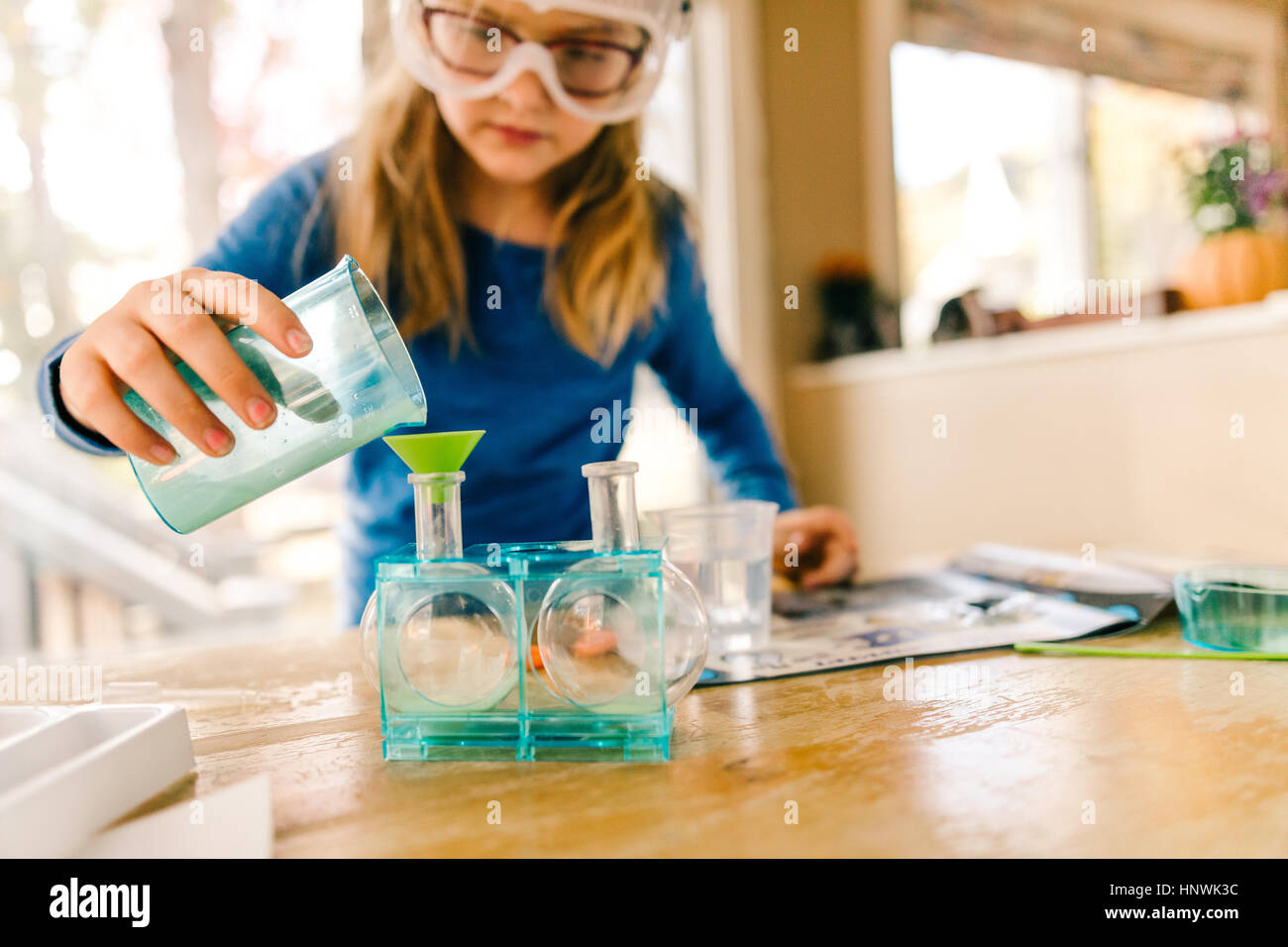 Girl doing science experiment, pouring liquid into flask Stock Photo