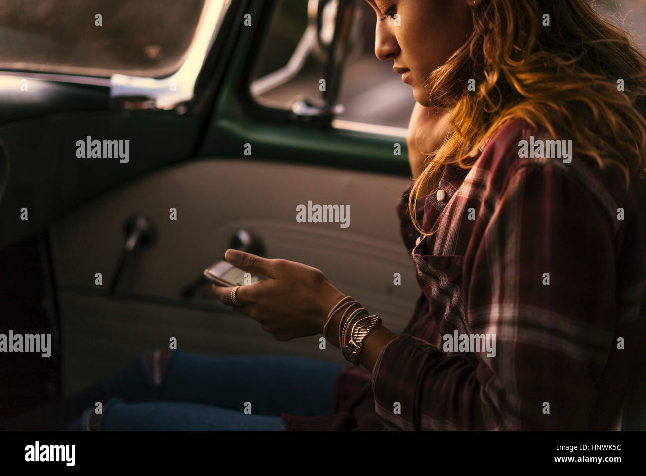 Young woman looking at smartphone in front seat of pickup truck at Newport Beach, California, USA Stock Photo