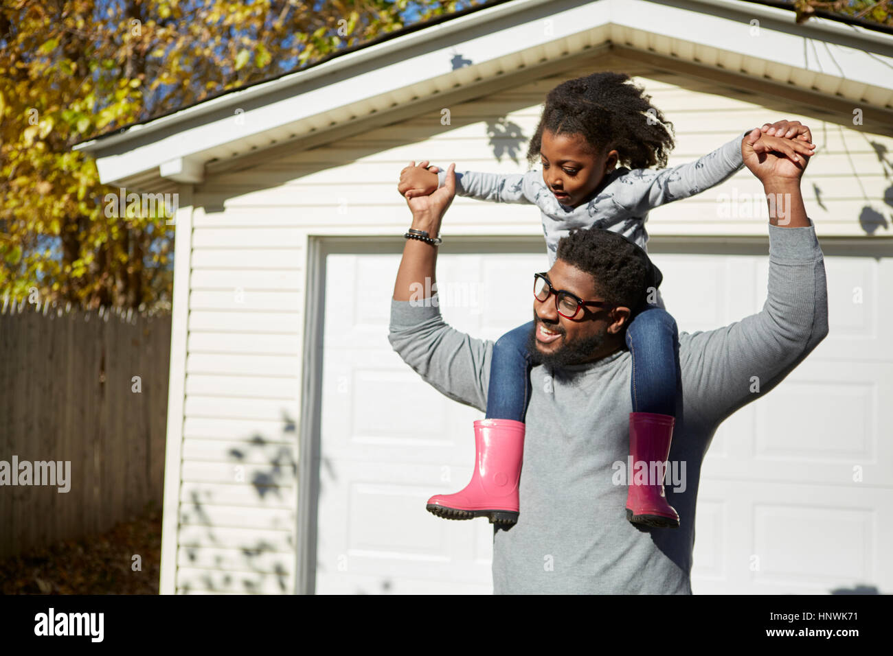 Mature man carrying daughter on shoulders by residential garage Stock Photo