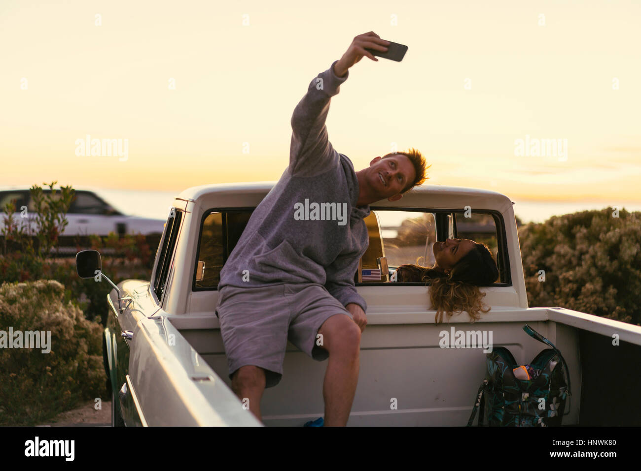 Man taking smartphone selfie with girlfriend in back of pickup truck at Newport Beach, California, USA Stock Photo