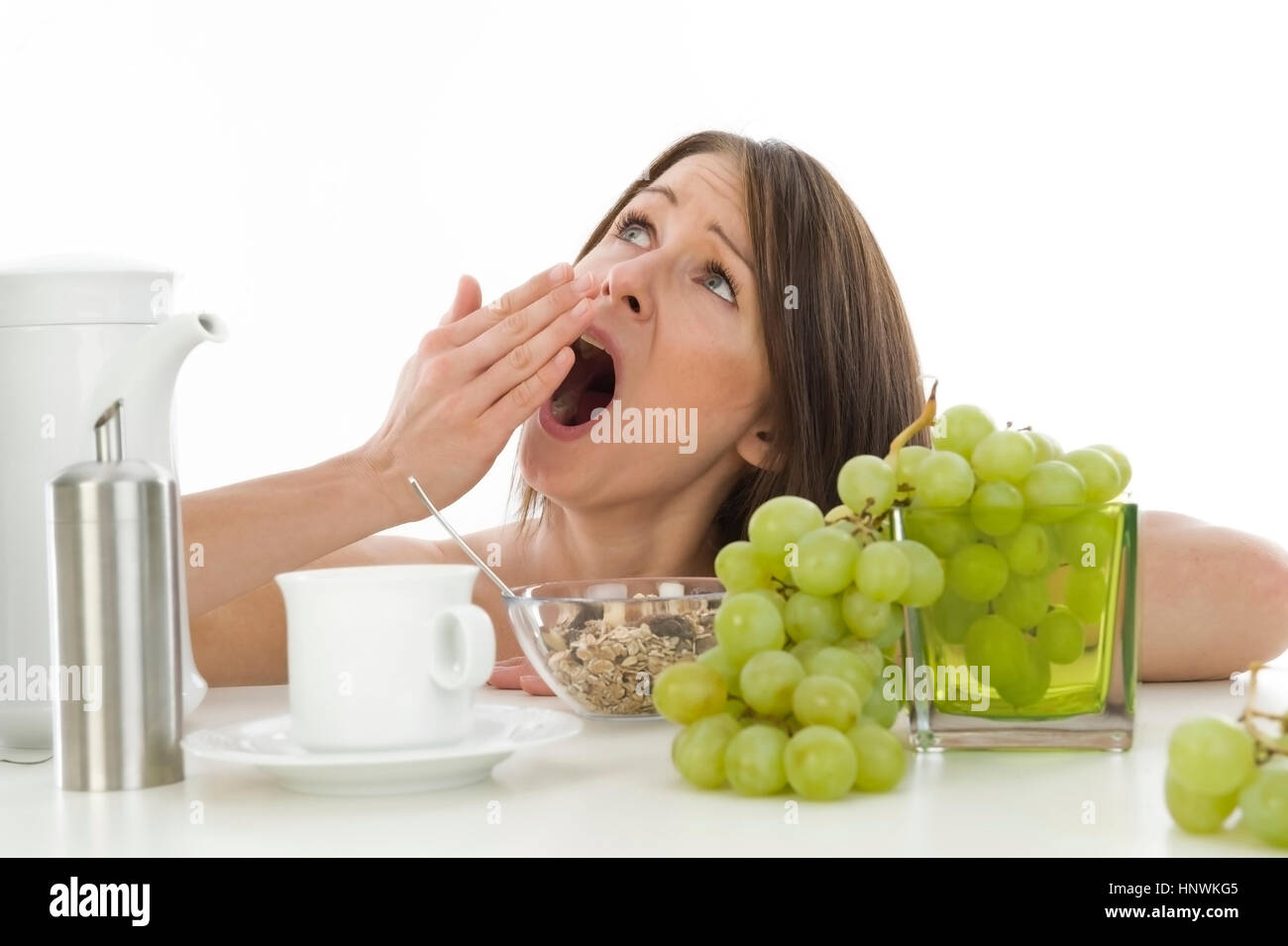 Model release, Unausgeschlafene, junge Frau gaehnt beim Fruehstueck - tired woman at breakfast Stock Photo