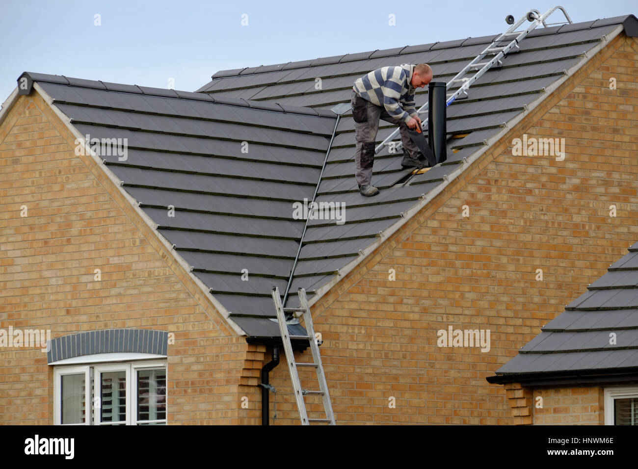 Workman on a house roof installing a chimney Stock Photo