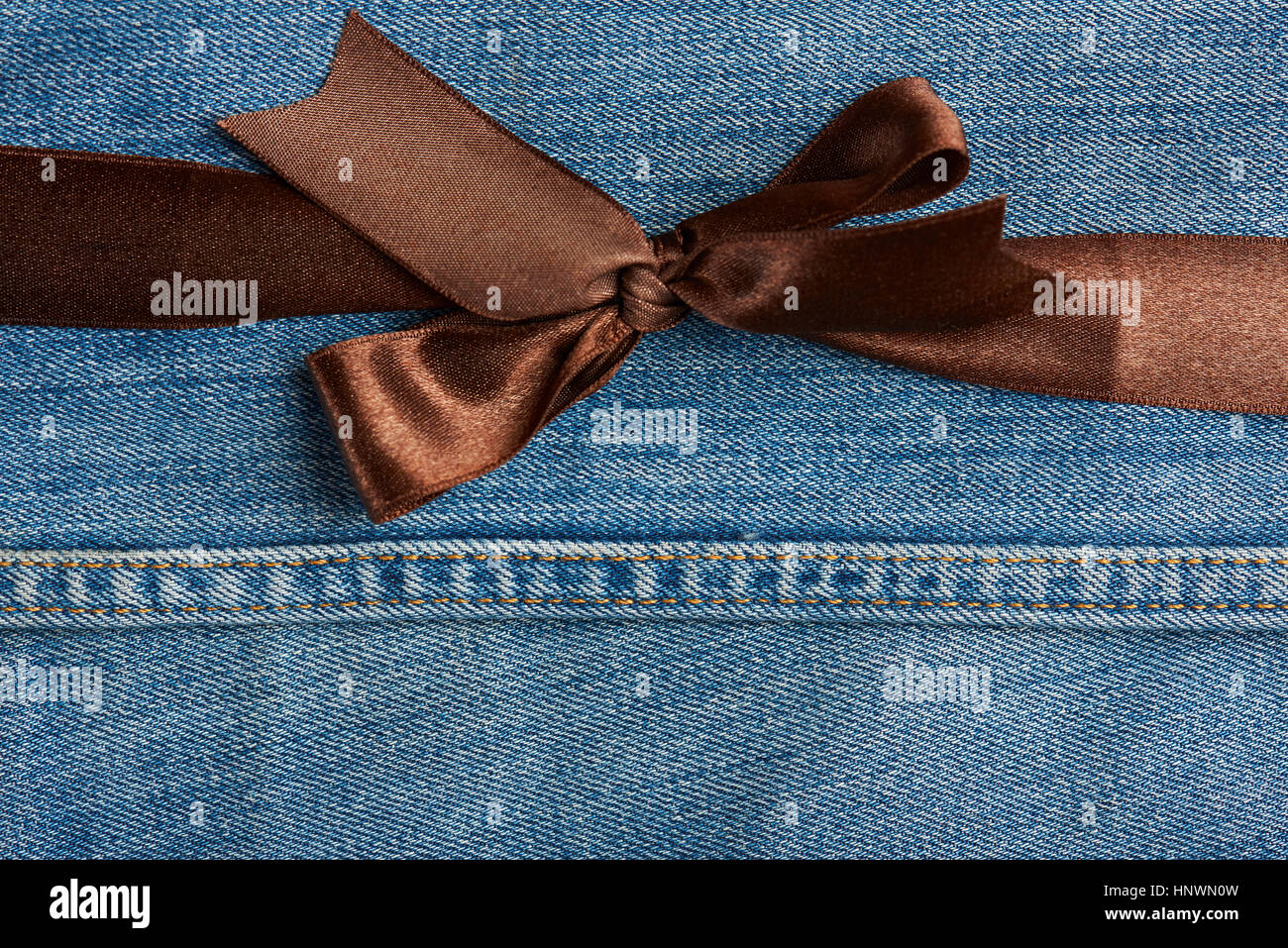 Brown bow on stitches blue jeans background Stock Photo