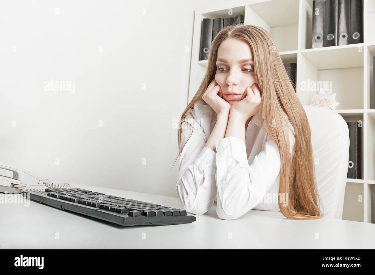 the young beautiful long-haired girl sits tired at office in the afternoon Stock Photo