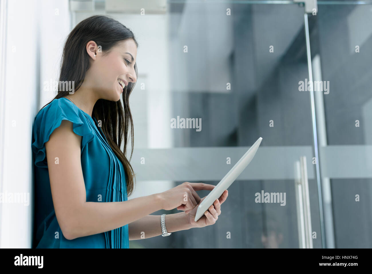 Window view of young businesswoman using digital tablet touchscreen at office entrance Stock Photo