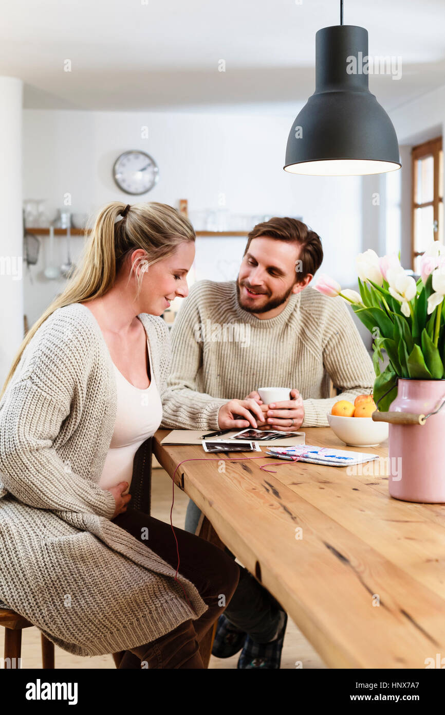 Pregnant mid adult couple looking at pregnancy scans on table Stock Photo