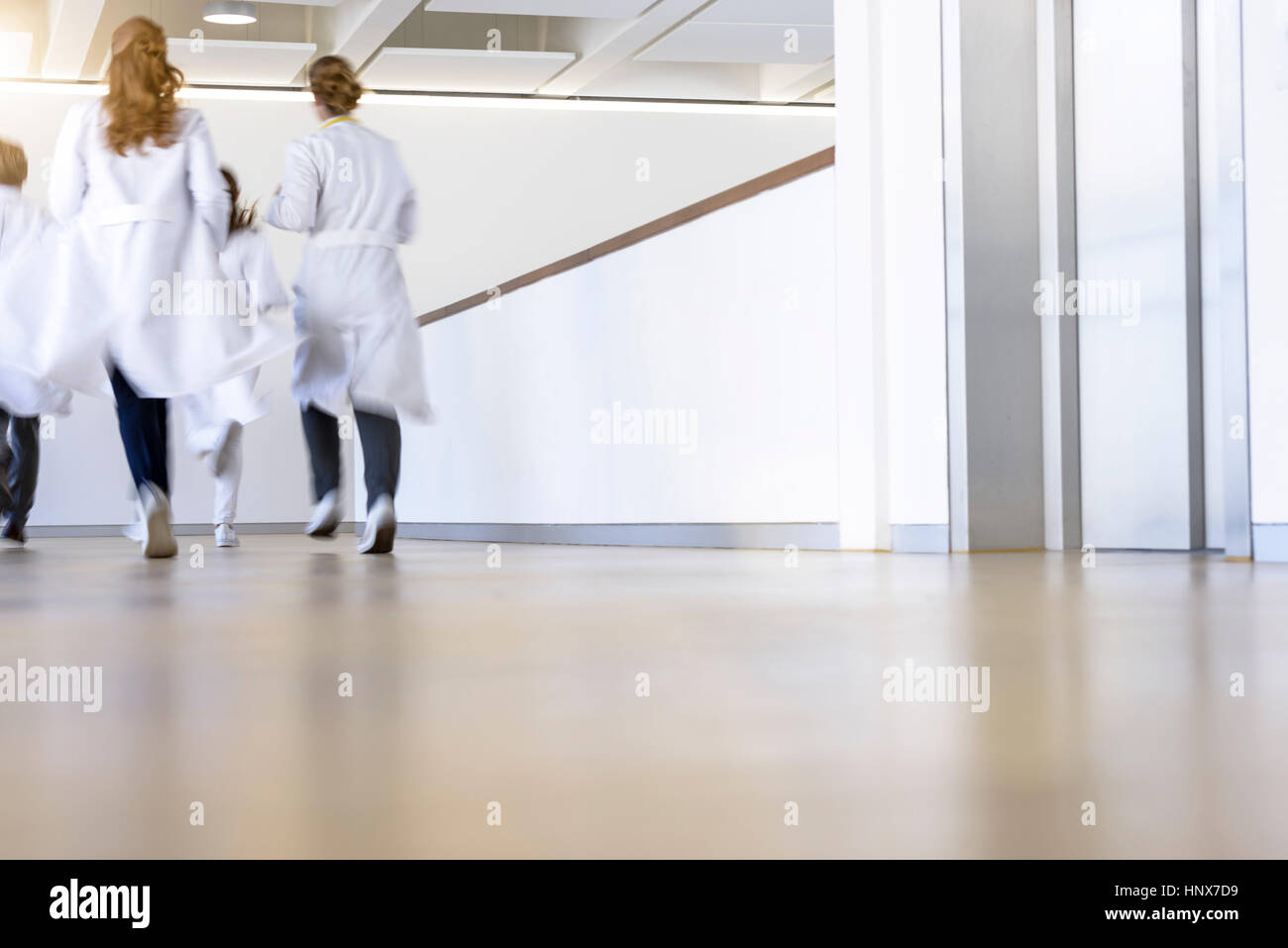 Rear view of male and female doctors running in hospital corridor Stock Photo