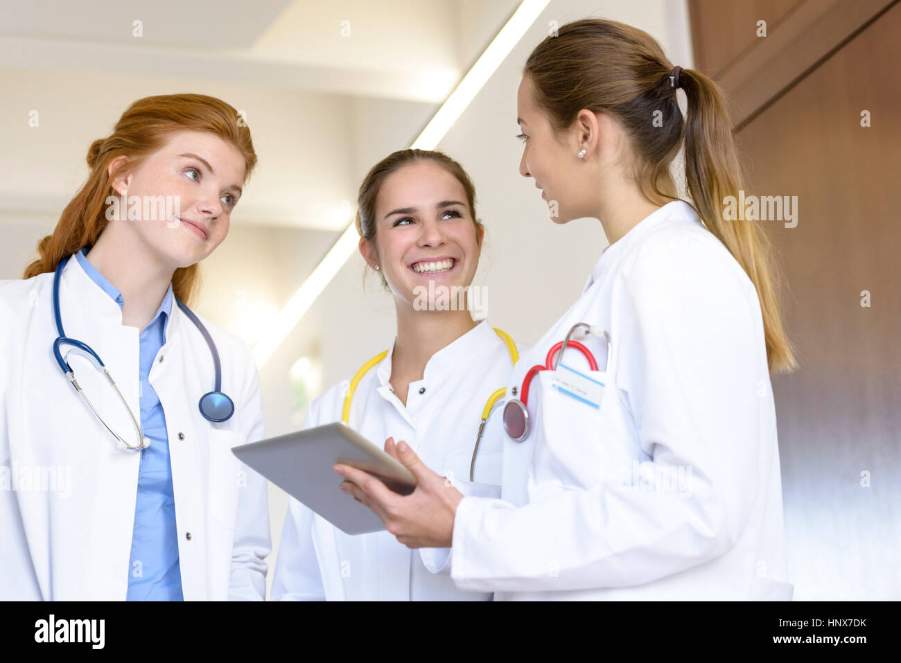 Three young female doctors with digital tablet having discussion in hospital Stock Photo