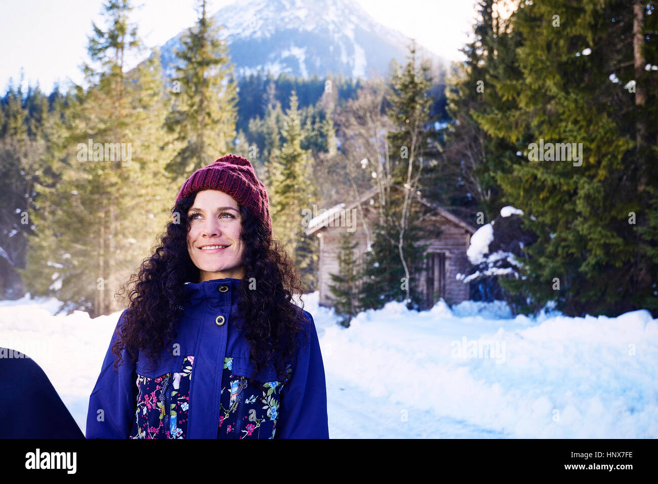 Woman in knit hat gazing by snowy forest, Austria Stock Photo