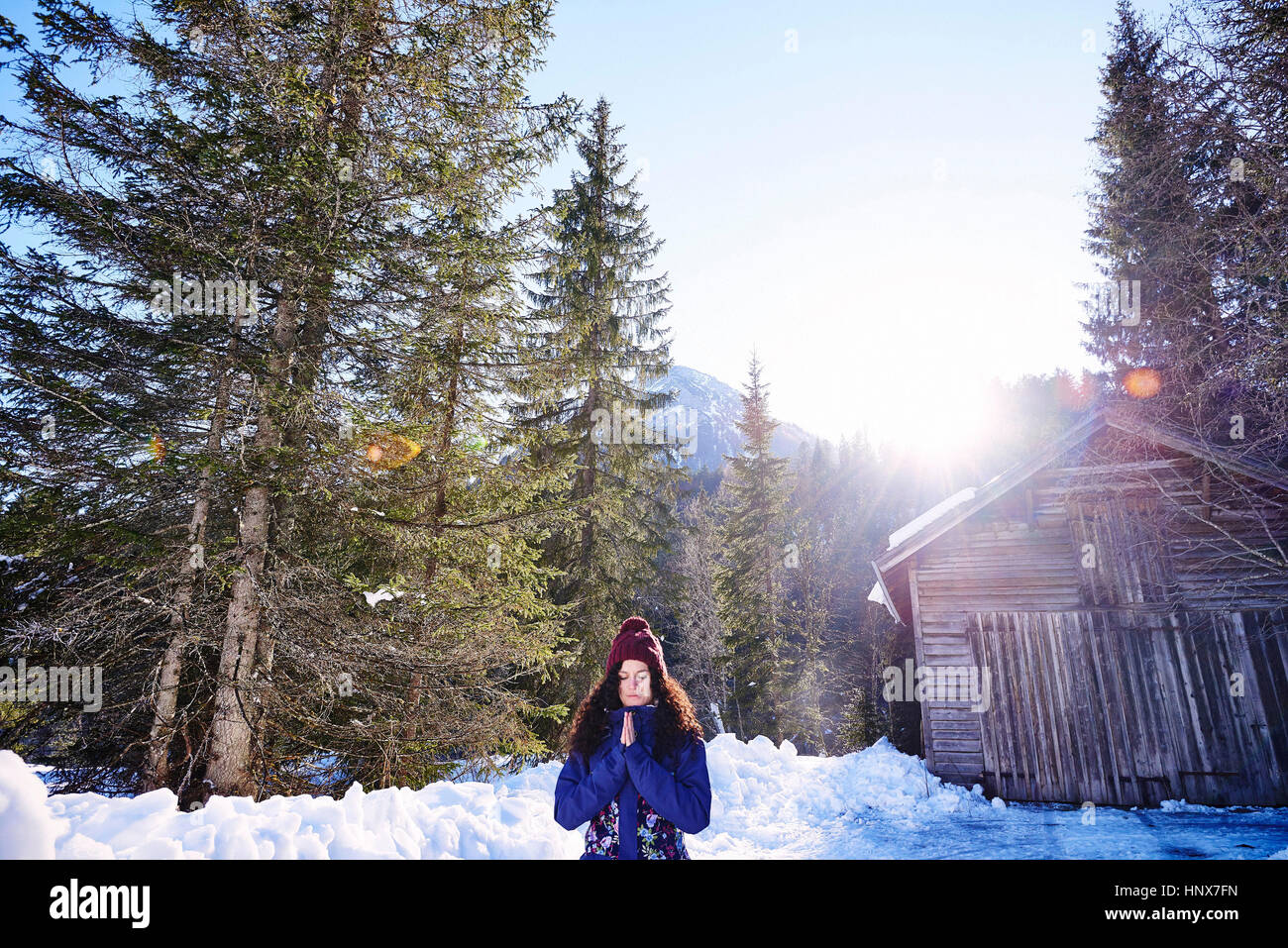 Woman practicing yoga, meditating in snowy sunlit forest, Austria Stock Photo