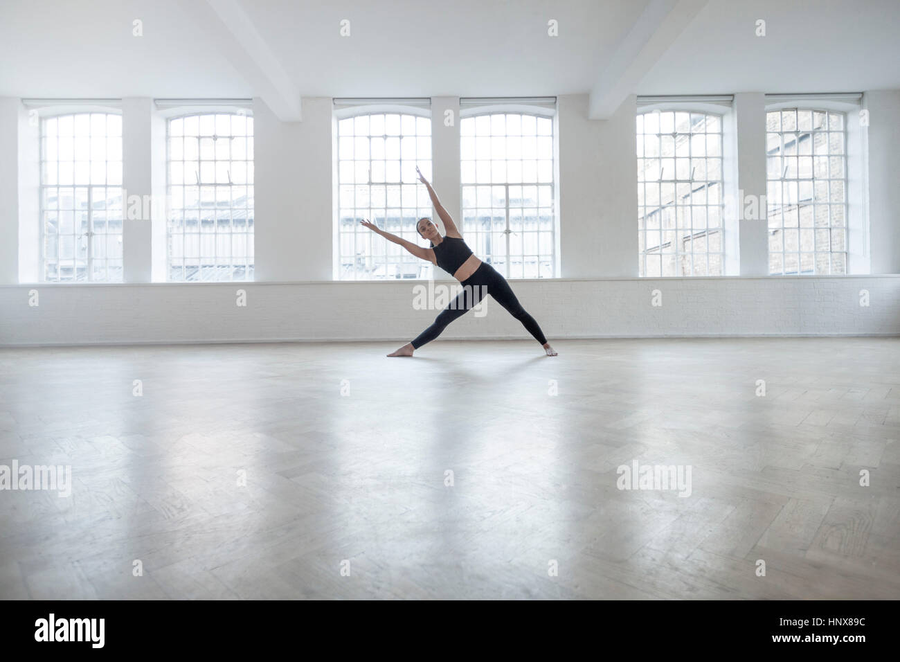 Woman in dance studio bending over sideways stretching Stock Photo