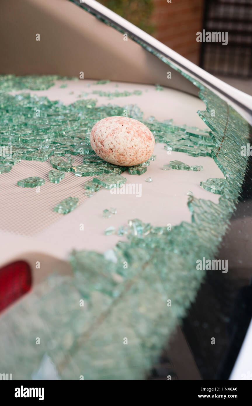 Rock through smashed car window Stock Photo