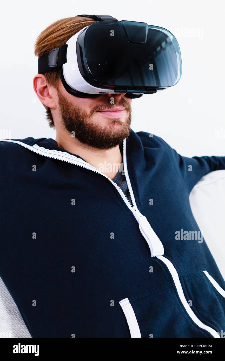 Mid adult man on sofa watching virtual reality headset Stock Photo