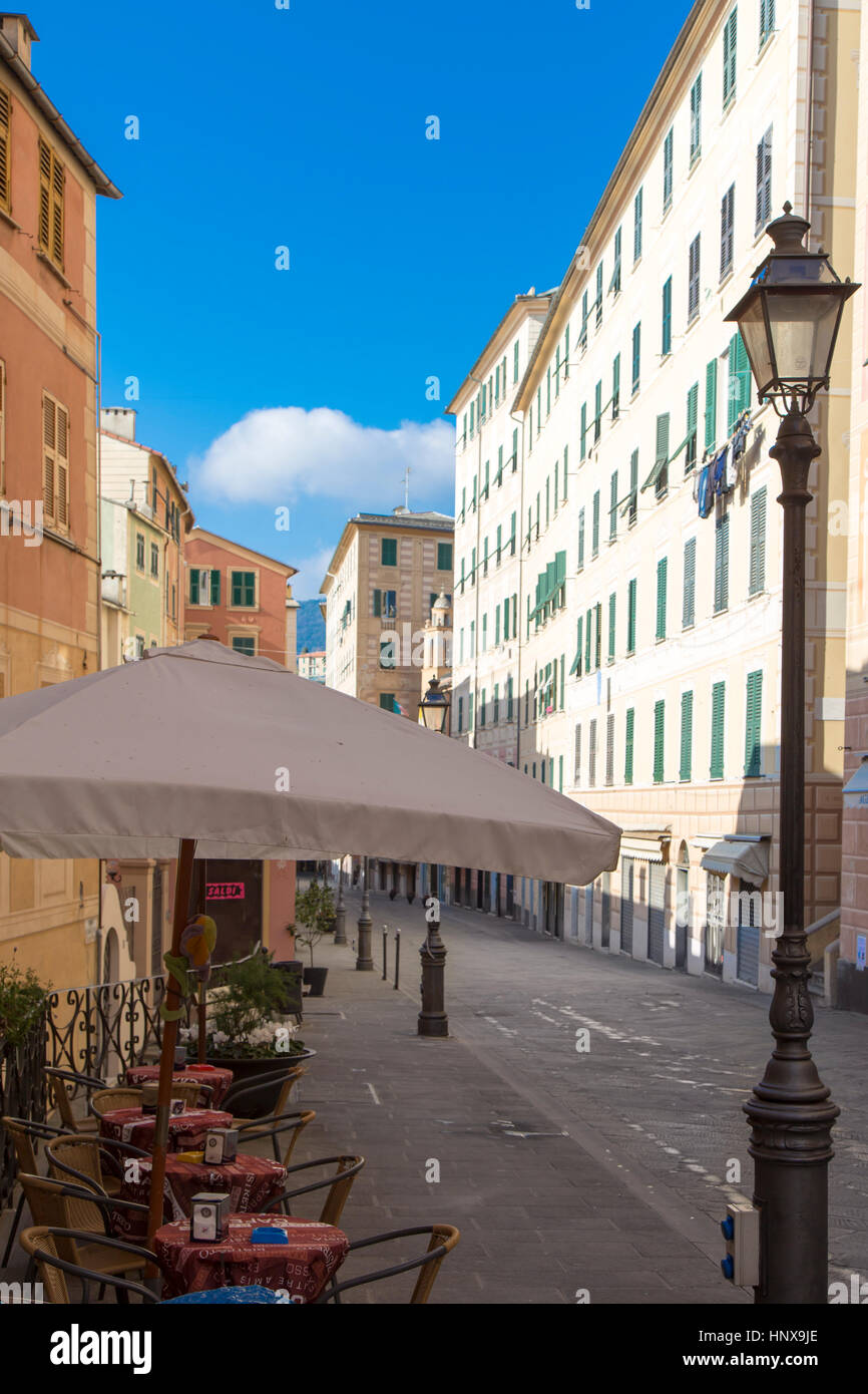 Outdoor cafeteria with tables and umbrellas in a narrow street in the resort fishing village of Camogli on the Italian Riviera, a popular tourist dest Stock Photo