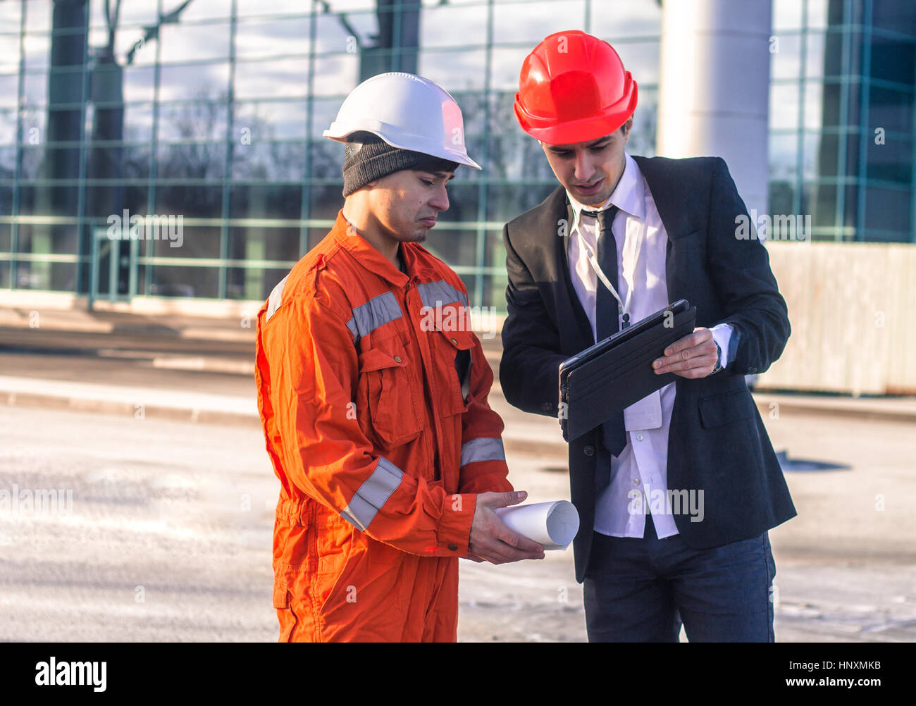young boss Scold Employee in conversation discussing a construction project on tablet. They wear  safety helmets. Business modern background Stock Photo