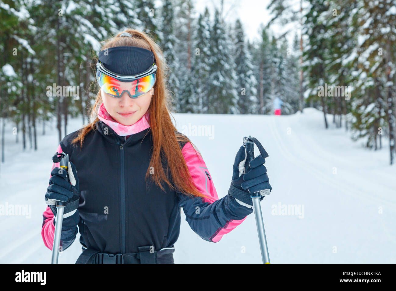 Cross-country skiing woman doing classic nordic cross country skiing in trail tracks in snow covered forest Stock Photo