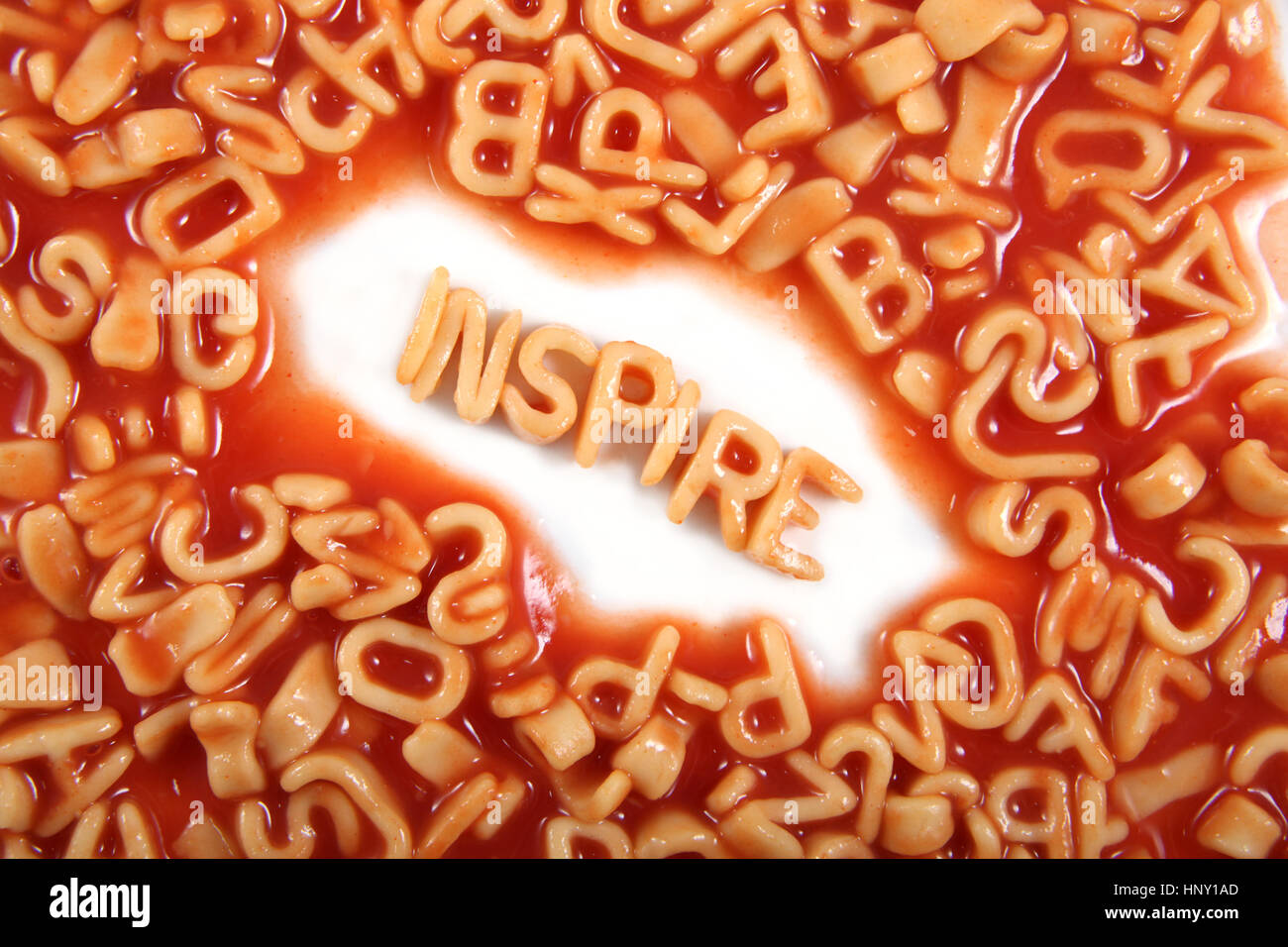 Inspire written in spaghetti pasta letters surrounded with jumbled letters. Stock Photo