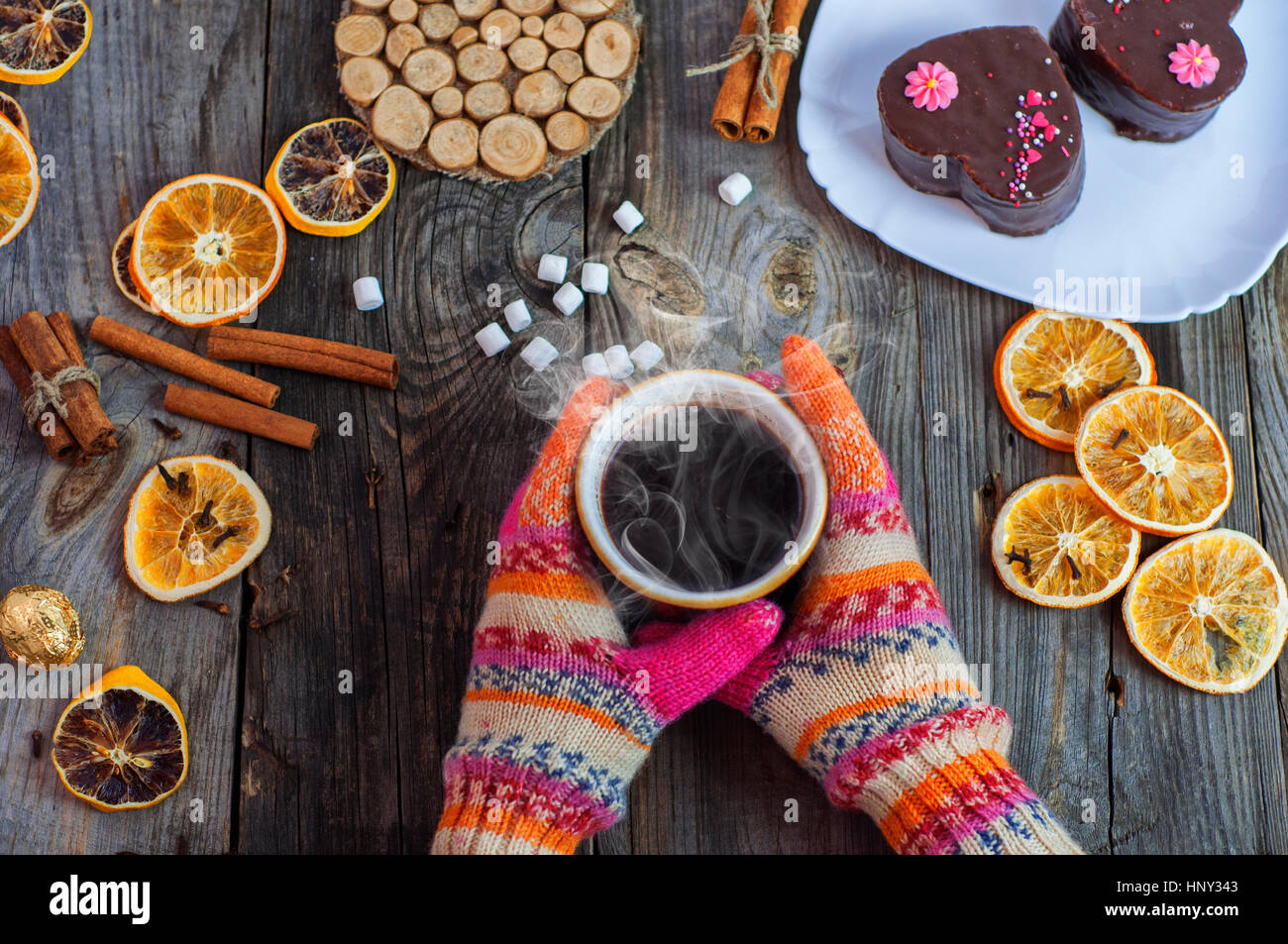 cup of black hot coffee in her hands, wearing colorful winter gloves on ...