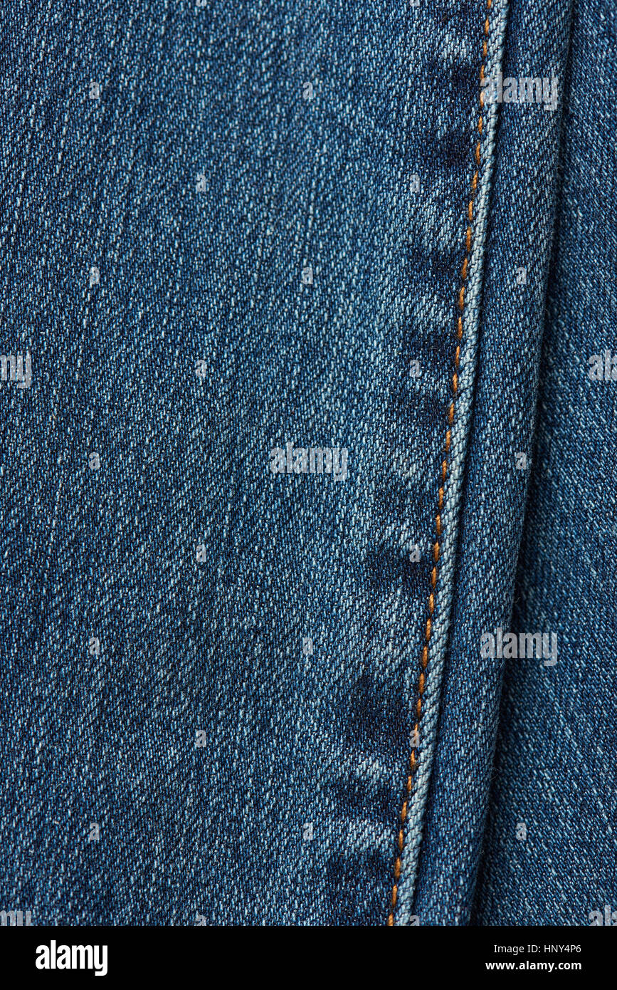 Stitches on jeans texture dark blue color. Jeans textile background. Orange stitches on jeans Stock Photo
