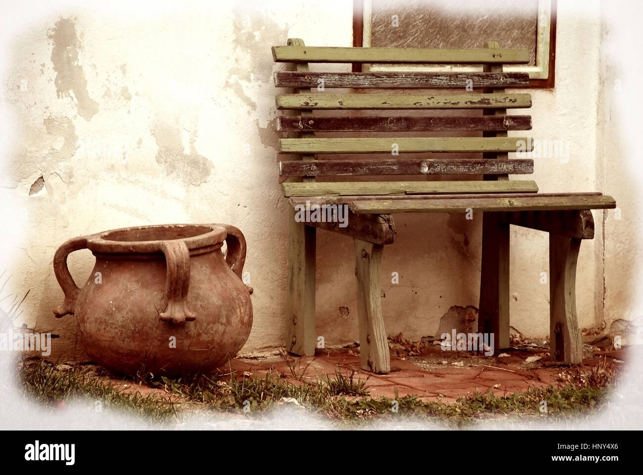 Bank neben Tontopf an alter Hausmauer - bench and bottle on an old house facade Stock Photo