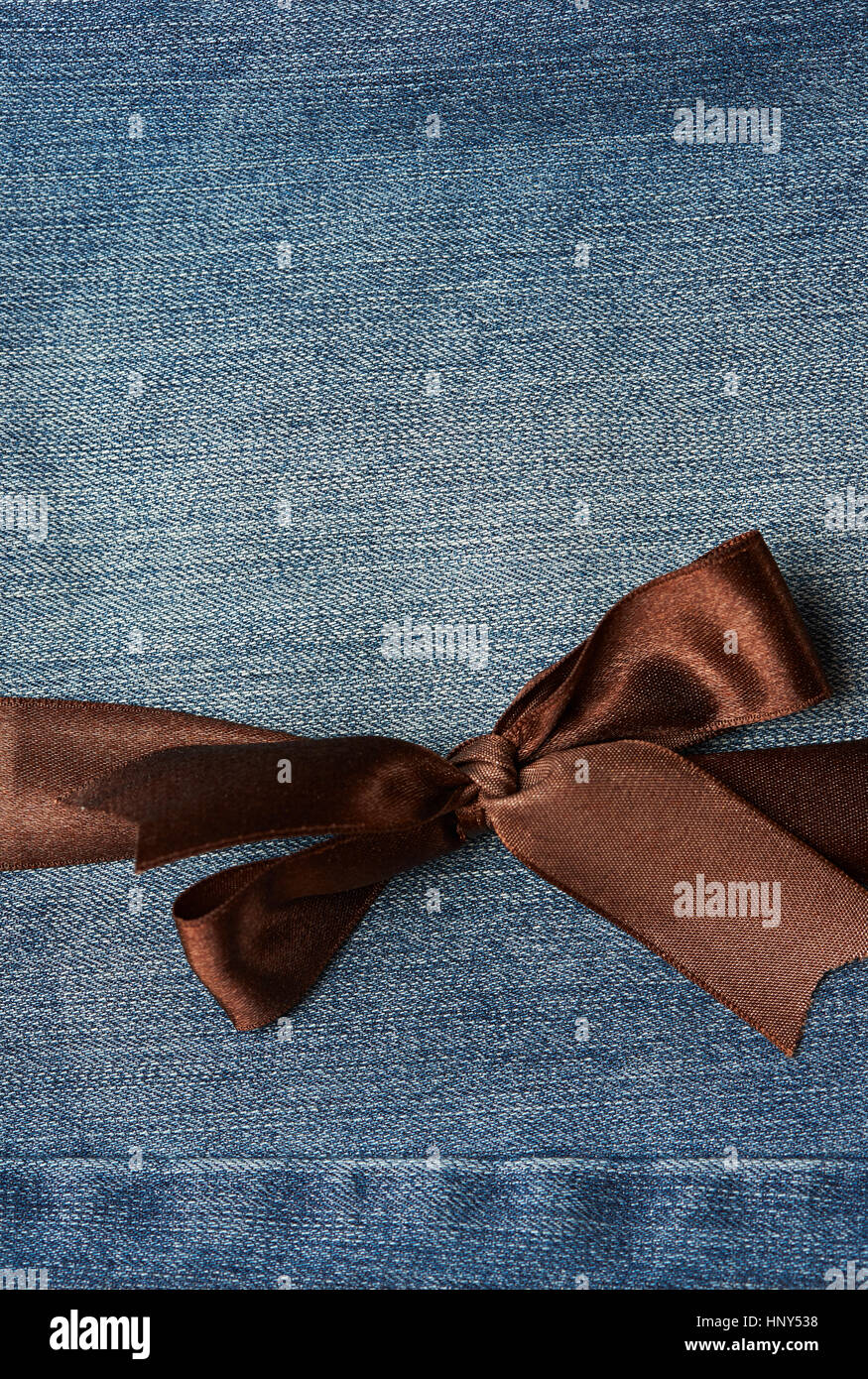 Brown bow on blue jeans textile texture background Stock Photo