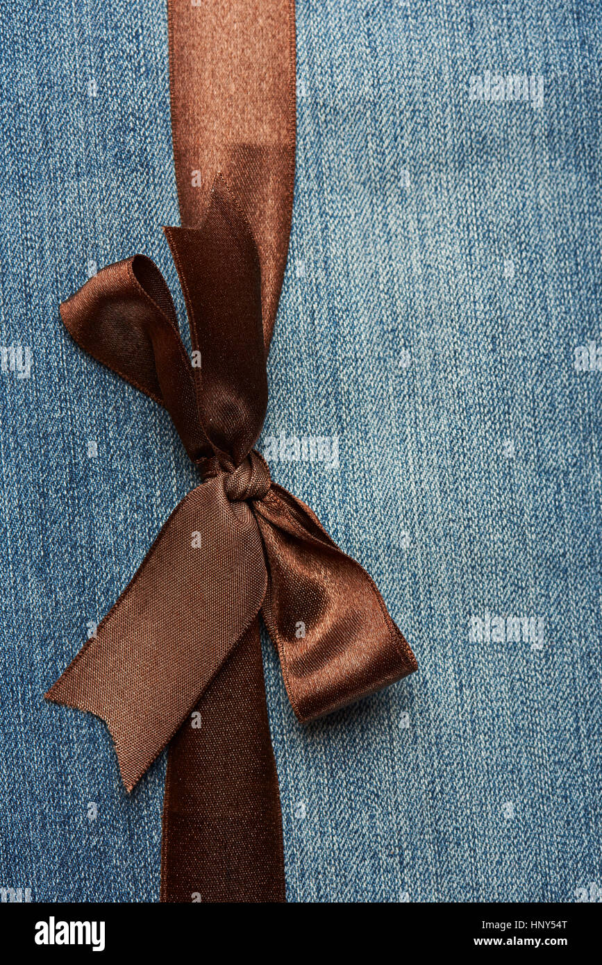 Close up of brown ribbon on blue jeans textile texture Stock Photo