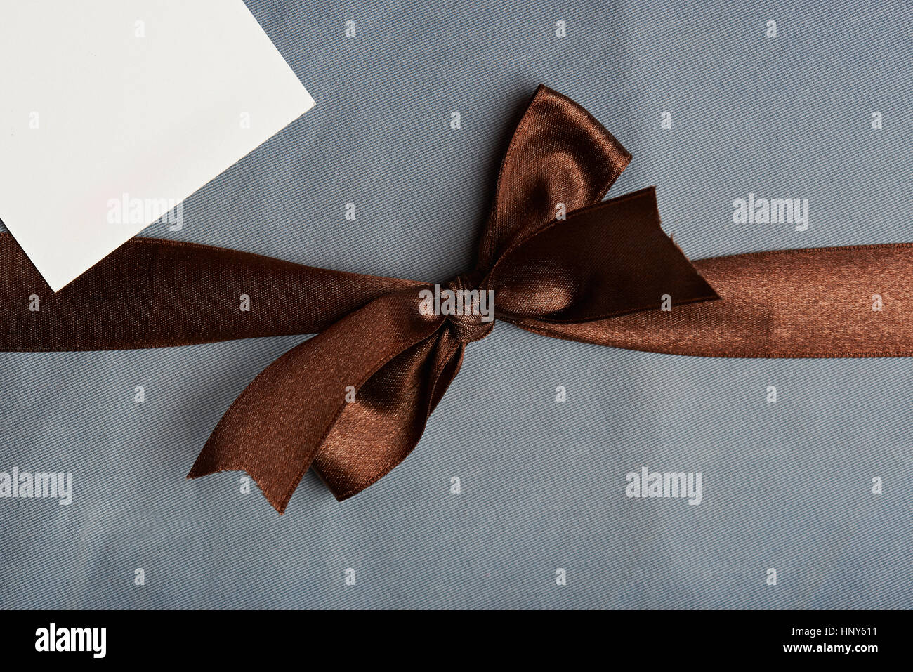 Brown ribbon on light blue background with white tag Stock Photo