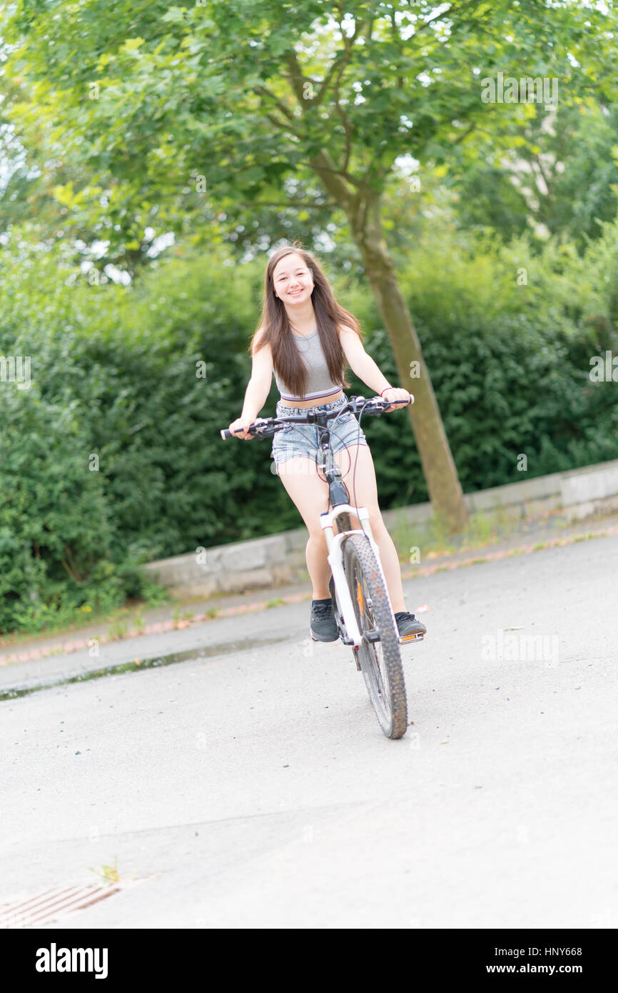 Teen girl riding bike in summer park Stock Photo