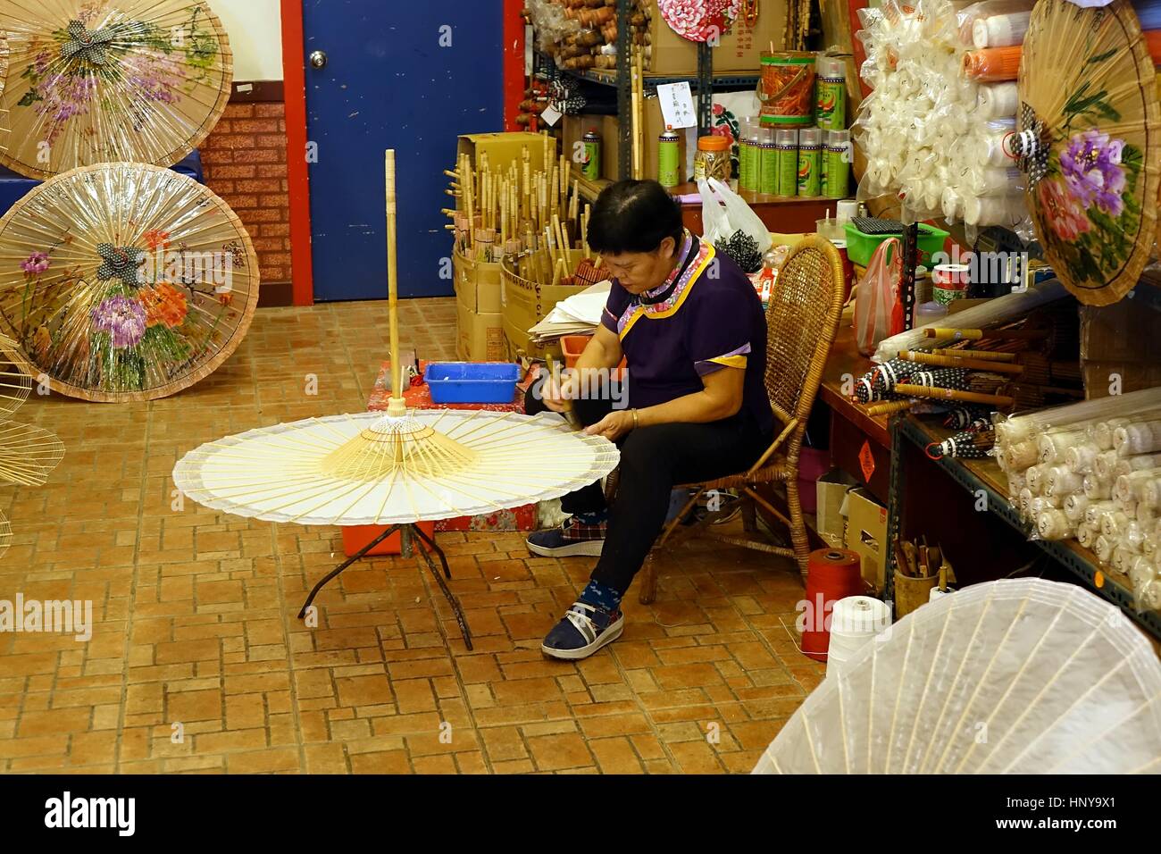 KAOHSIUNG, TAIWAN -- JULY 24, 2016: A female craftsperson makes oil-paper umbrellas, which is a traditional art and craft product by the Chinese Hakka Stock Photo