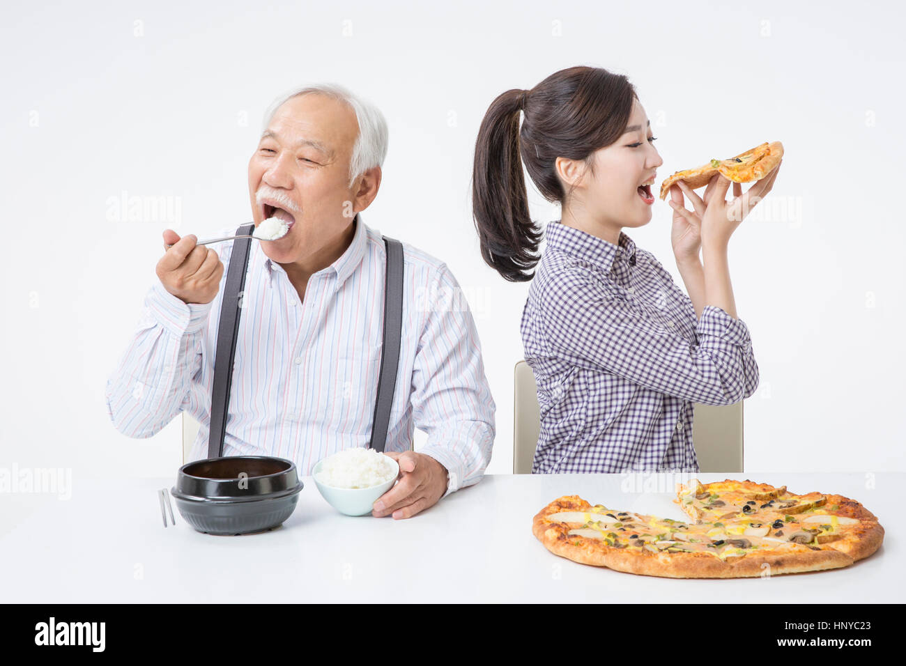 Senior man eating rice and young woman eating pizza Stock Photo