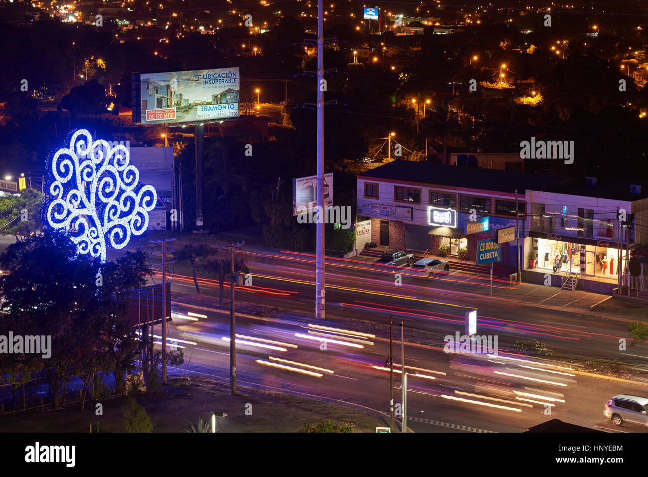 Managua, Nicaragua - January 5, 2017: Metal tree next to highway with blurred car lights at night Stock Photo